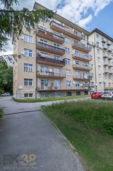 Bytový dům ve Vysokých Tatrách s balkóny a parkovištěm před budovou.
