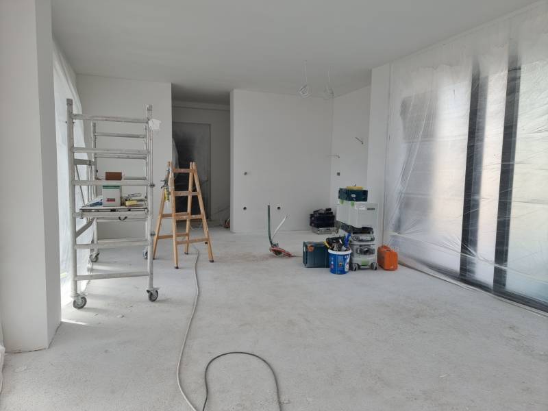 Renovace interiéru ve vile s žebříkem, nářadím a fólií na podlaze.