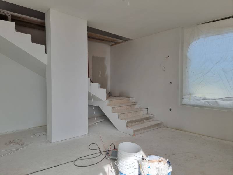 Schodiště ve vile během renovace, vedle velkého okna se zakrytým výhledem.