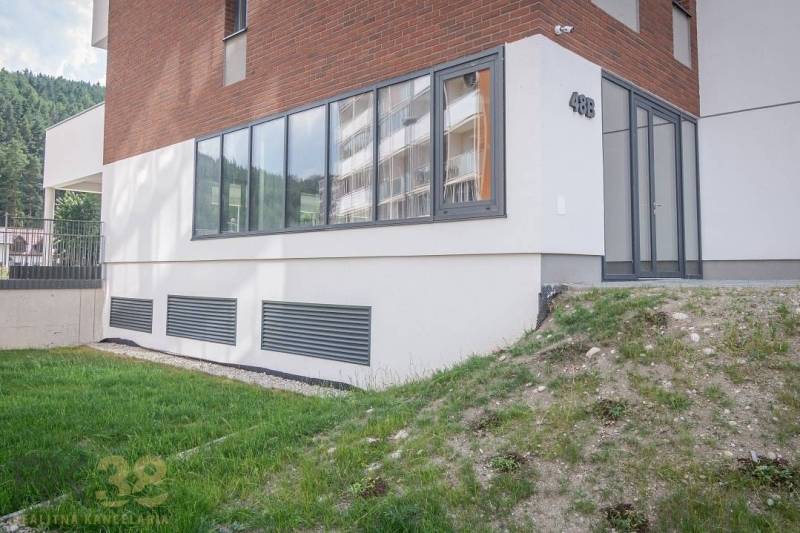 Fasáda obchodních prostor ve městě Svit s velkými okny a zeleným trávníkem.