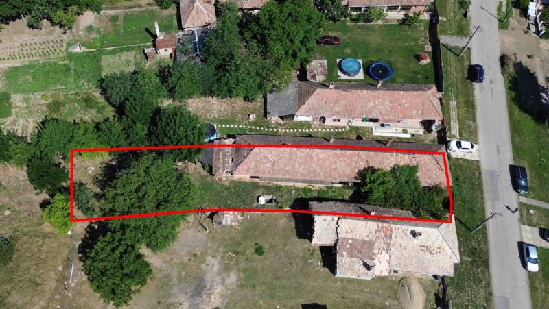 Rodinný dům v Hronovcích s pozemkem obklopený zelení a sousedními budovami.