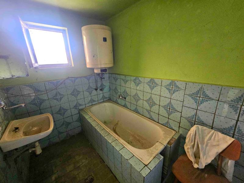 Koupelna s vanou a umyvadlem v rodinném domě s modrými dlaždicemi.