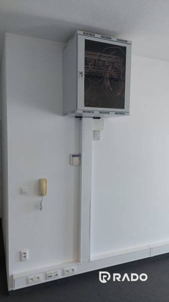 Kanceláře s komunikačním zařízením a síťovým rozvaděčem na bílé stěně.