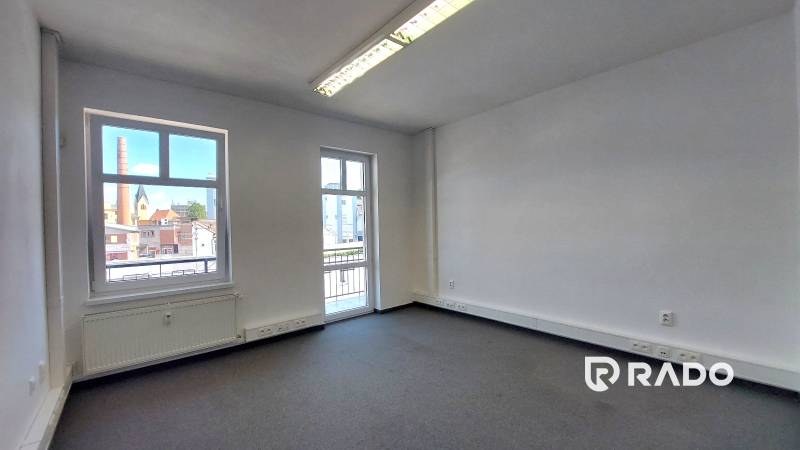 Prostorné kanceláře s oknem a balkonem, nabízející výhled na město.