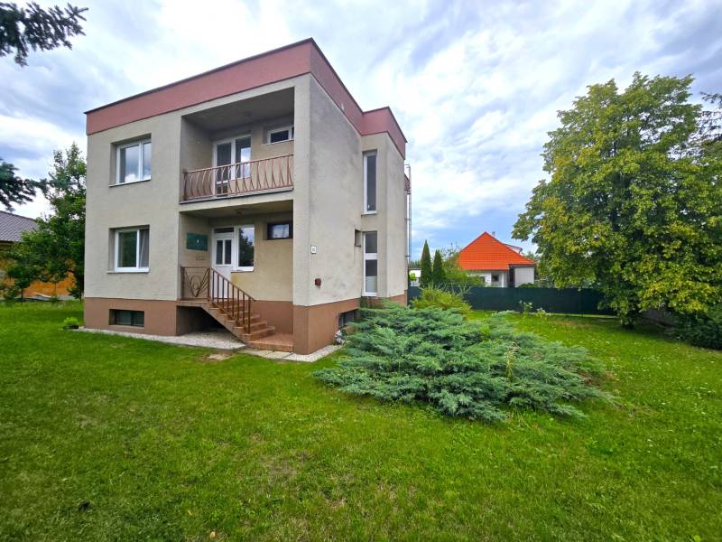 Dvoupatrový rodinný dům v Novém Městě nad Váhom s trávníkem a stromem.