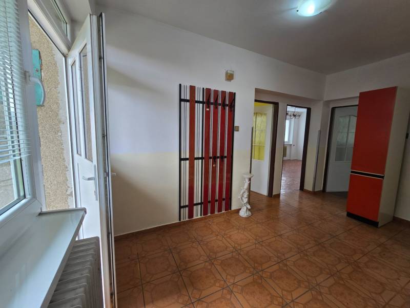 Interiér rodinného domu s otevíratelným oknem, dveřmi, věšáky a dlažbou.
