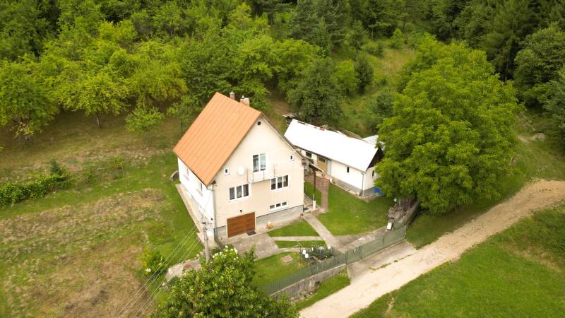 Rodinný dům v Papradně obklopený travnatým pozemkem a stromy, přístupová cesta.