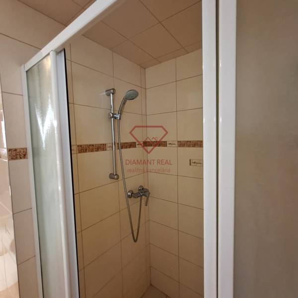 Sprchový kout v rodinném domě s keramickým obkladem a nastavitelnou sprchovou hlavicí.