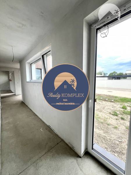 Chodba s okny a vstupem v rodinném domě. Na podlaze je beton.