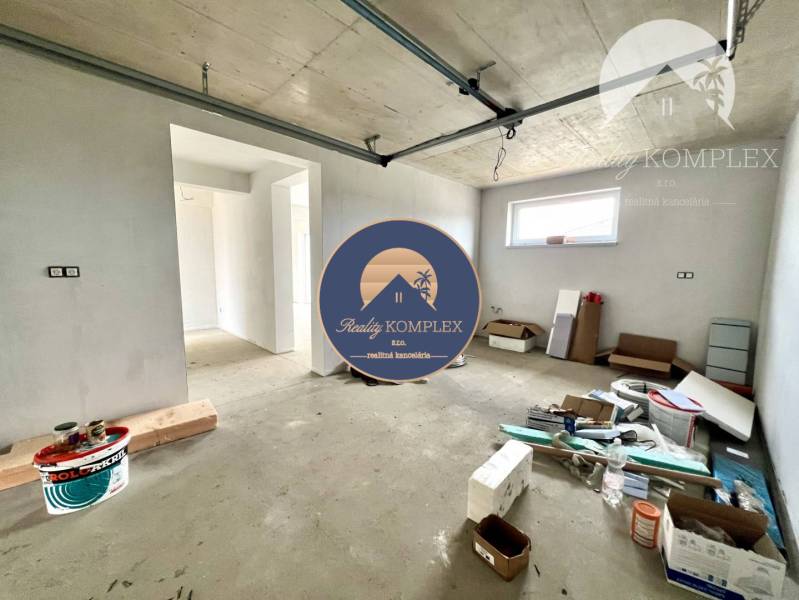 Nedokončený interiér rodinného domu s rozloženým stavebním materiálem a novými stěnami.