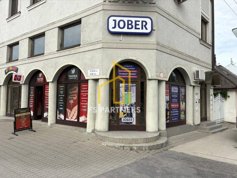 Komárno, ulice Petőfiho, obchodní prostory s reklamními tabulemi a několika vchody.