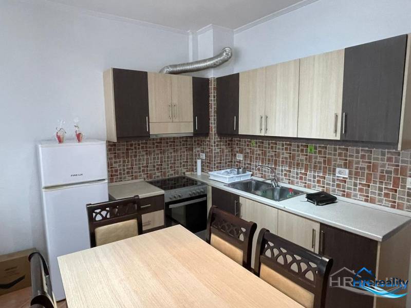 Kuchyně v rekreačním apartmánu s jídelním stolem a bílými spotřebiči.