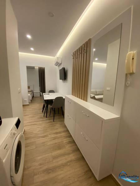 Chodba rekreačního apartmánu s pračkou, zrcadlem a jídelním stolem.
