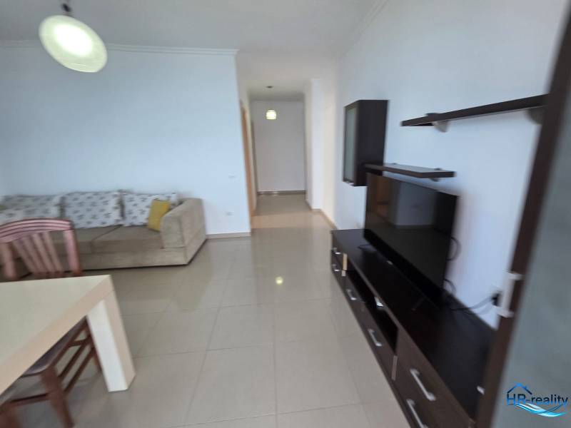 Obývací pokoj s pohovkou, televizí a jídelním stolem v rekreačním apartmánu.