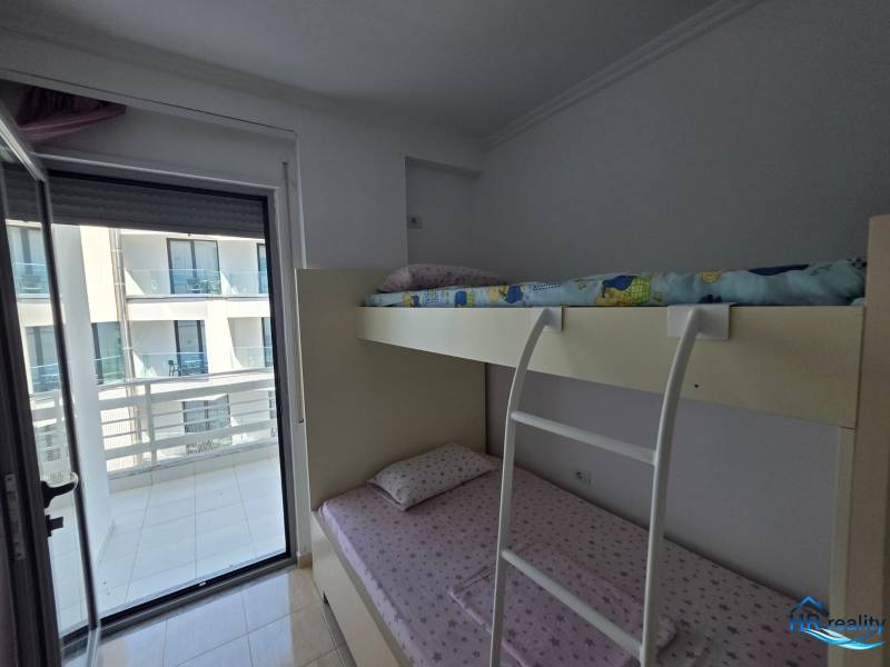 Patrová postel v ložnici rekreačního apartmánu, s výhledem na balkon.