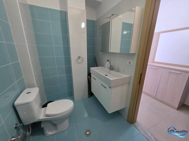 Koupelna se světle modrými dlaždicemi v Rekreačním apartmánu, umyvadlo a zrcadlová skříňka.
