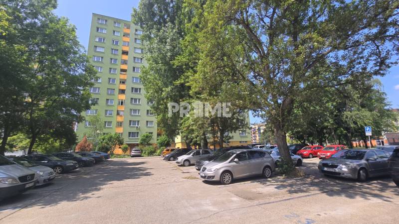Parkoviště v Bratislavě - Petržalce na ulici Osuského s výhledem na bytové domy a zeleň.