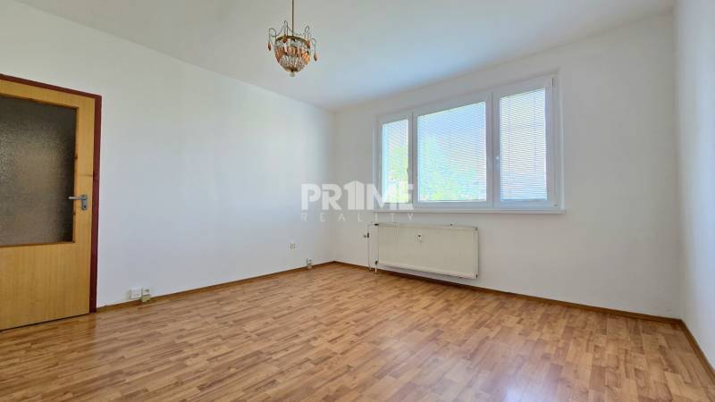 Pokoj v 3-pokojovém bytě s laminátovou podlahou, velkým oknem a centrálním osvětlením.