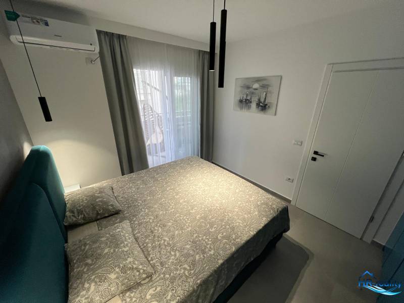 Rekreační apartmán s pohodlnou postelí, klimatizací a balkonovými dveřmi s výhledem.