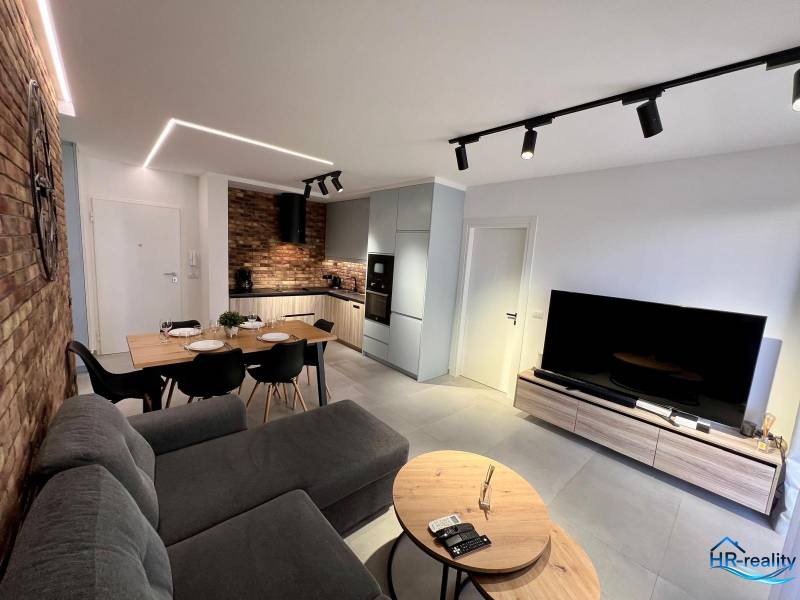 Obývací pokoj rekreačního apartmánu je vybaven kuchyní, jídelním stolem a pohodlnou pohovkou.