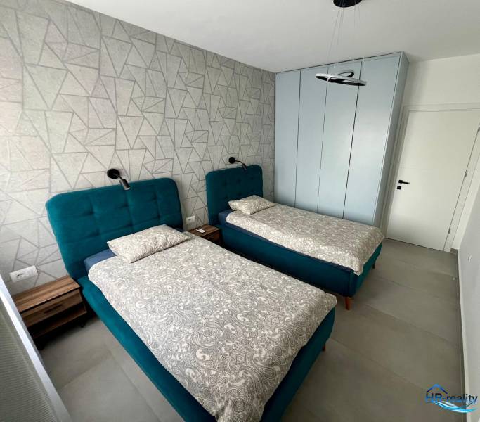 Dvoulůžkový pokoj s modrými postelemi a vzorovanou stěnou v Rekreačním apartmánu.