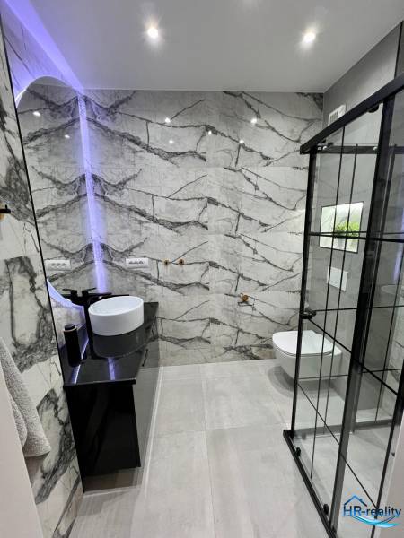 Koupelna v rekreačním apartmánu s designovým umyvadlem a sprchovým koutem.