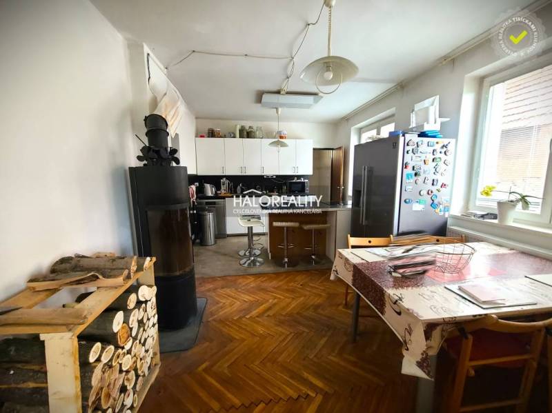 Kuchyně rodinného domu se sporákem, jídelním stolem a lednicí na barevné podlaze.