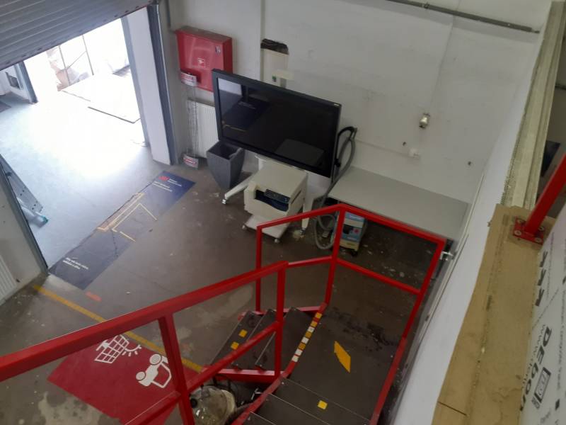 Ve skladech a halách je červené schodiště, obrazovka a otevřený vstupní prostor.