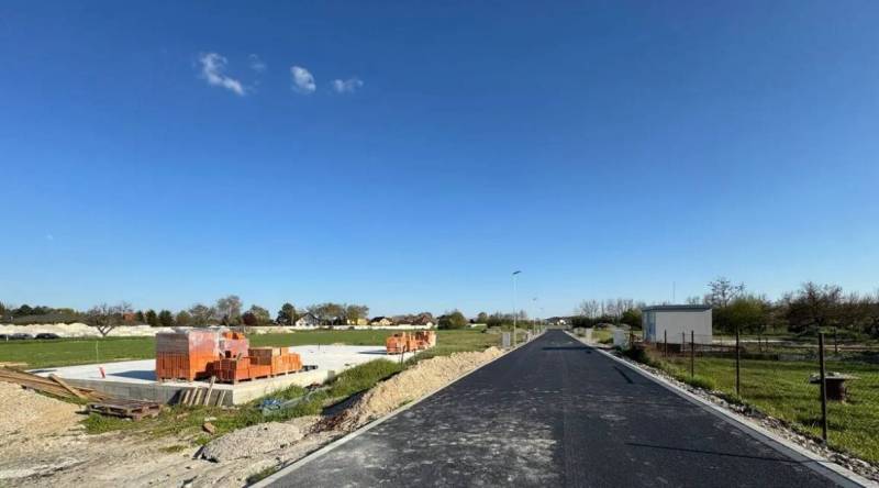 Stavební pozemek rodinného domu v Horním Baru s cihlami a novou asfaltovou cestou.