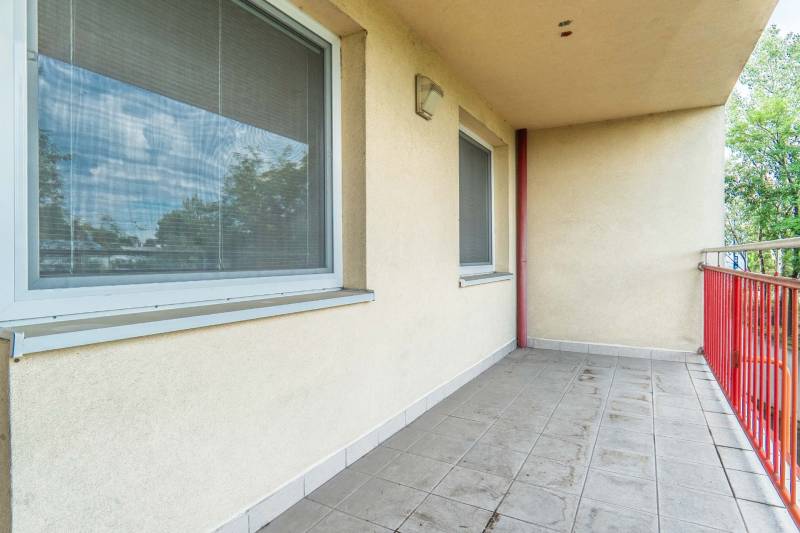 Balkon s dlažbou a dvěma okny v 2-pokojovém bytě.