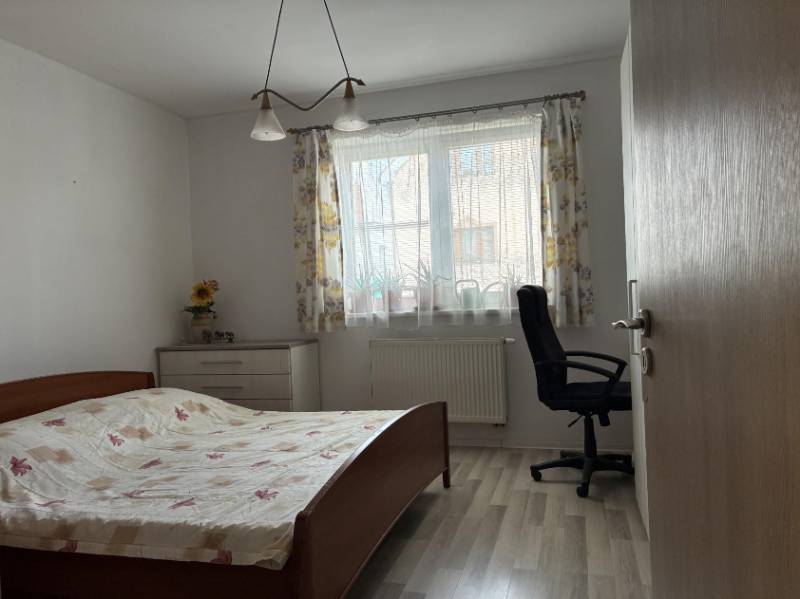 Ložnice s postelí, pracovní židlí a komodou v rodinném domě.