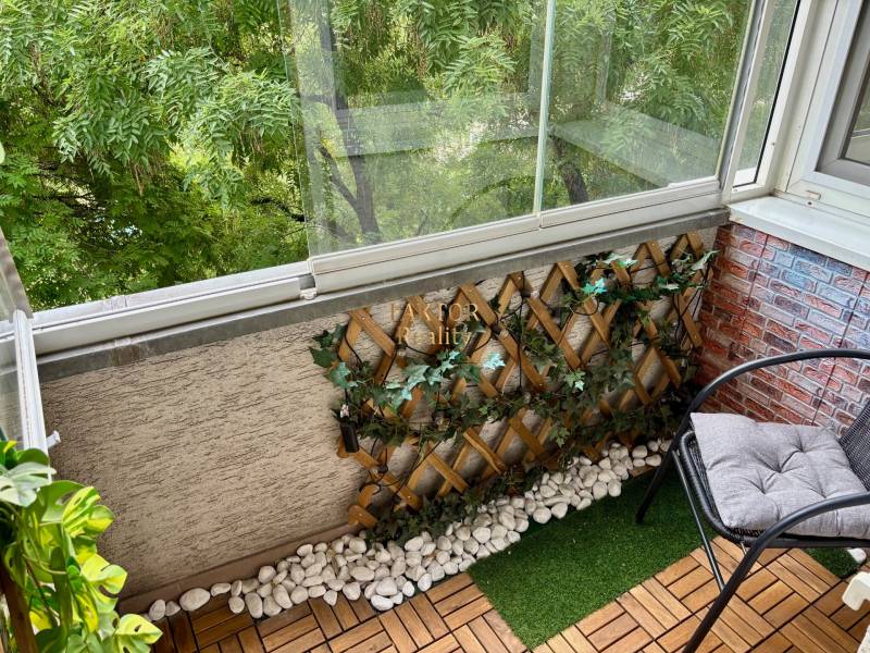 Zasklený balkon s křeslem a rostlinami, součástí 2pokojového bytu.