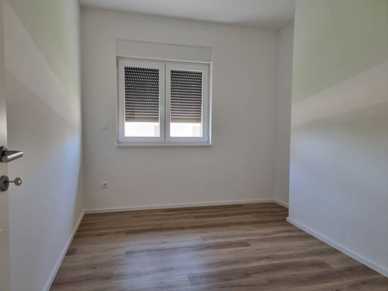 Pokoj s dřevěnou podlahou a oknem ve 4-pokojovém bytě.