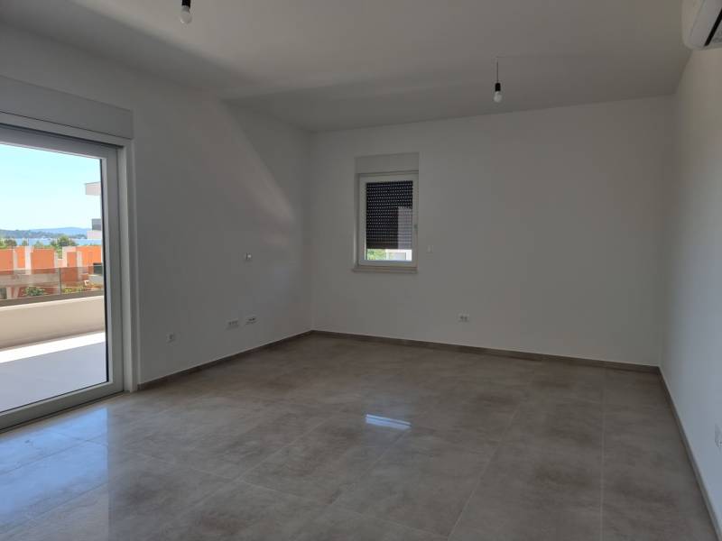 Prostorný pokoj čtyřpokojového bytu s výhledem do exteriéru přes balkónové dveře.