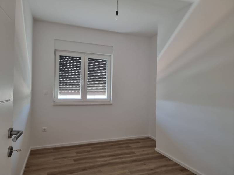 Interiér 4-pokojového bytu s dřevěnou podlahou a zataženými žaluziemi na okně.