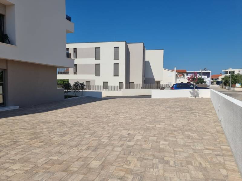 Parkoviště u 4pokojového bytu ve městě Vodice se zpevněným povrchem a čistou architekturou.