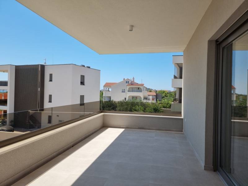 Balkon s výhledem na sousední budovy ve Vodicích nabízí prostor k odpočinku.
