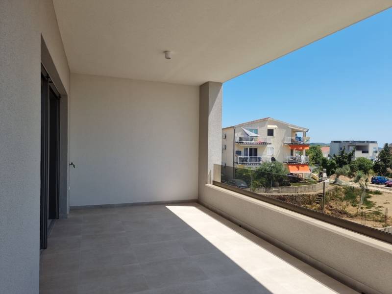Balkon ve 4pokojovém bytě ve Vodicích s výhledem na okolní budovy a zeleň.