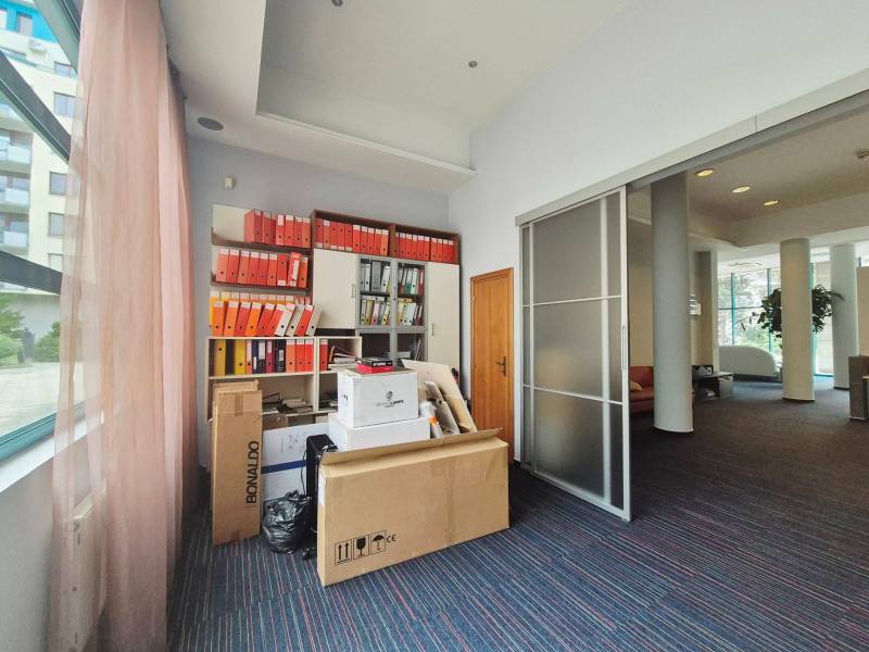 Obchodní prostory s kartotékou a balíky v kanceláři, prosvětlené velkými okny.