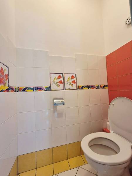 Toaleta s barevnými dlaždicemi a květinovým vzorem v obchodních prostorách.