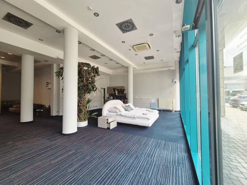 Obchodní prostory s postelí, vysokými sloupy a velkými okny.