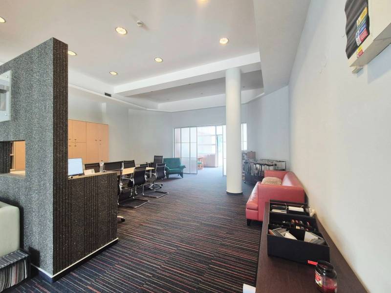 Obchodní prostory s konferenčním stolem, červenou sedačkou a moderním nábytkem.