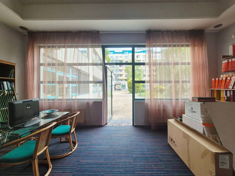 Obchodní prostory s prosklenou stěnou, počítačem, stolem a regálem se šanony.