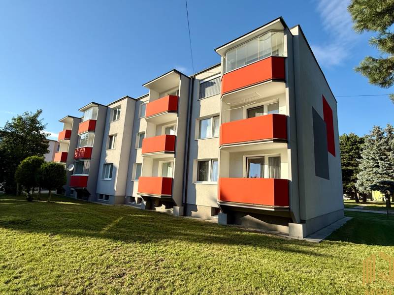 Exteriér bytového domu na sídlišti v Jablonici s červenými balkony.