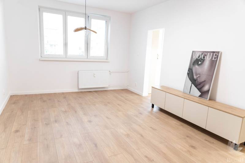 Světlý pokoj v 2-pokojovém bytě s dřevěnou podlahou a dekorací.