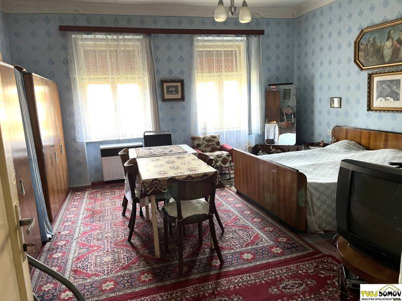 Ložnice v rodinném domě s dřevěným nábytkem, koberec a dekorace na stěnách.