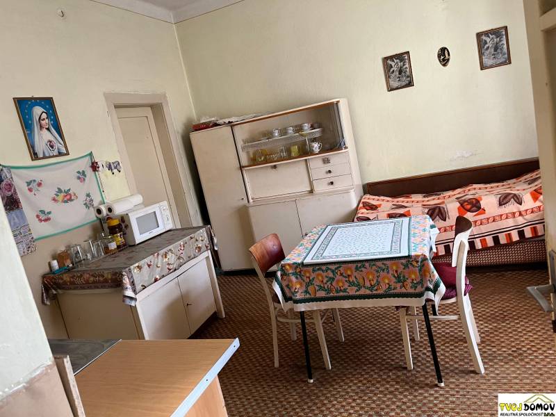 Kuchyně v rodinném domě s jídelním stolem, mikrovlnkou a pohovkou.