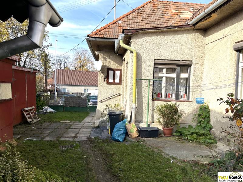 Rodinný dům na Partizánské ulici v Detvě s dvorem, rostlinami a odvodňovacími trubkami.