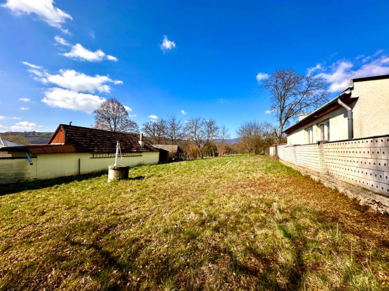 Výstavba domů v Moravském Lieskovém, zobrazené travnaté pozemky a okolní stavby.