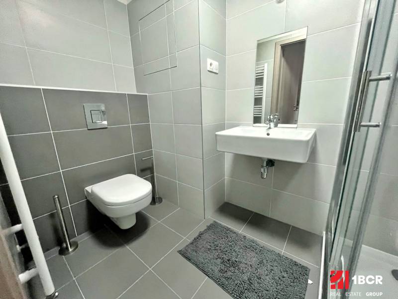Koupelna v 1-pokojovém bytě se sprchovým koutem, umyvadlem a závěsným WC.